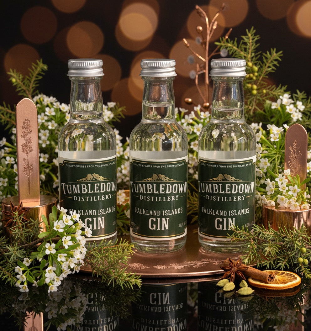 Three bottles of Tumbledown Distillery gin on a decorative tray with a bokeh background